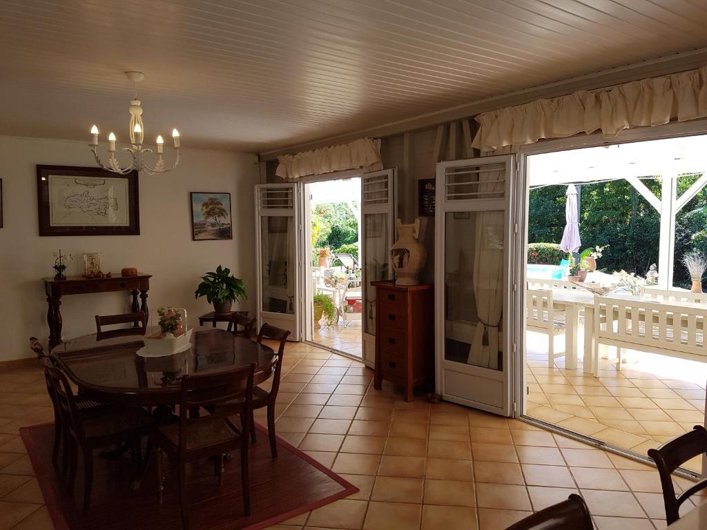 una sala da pranzo con tavolo e sedie e un patio di L'Ecrin Vert a La Trinité