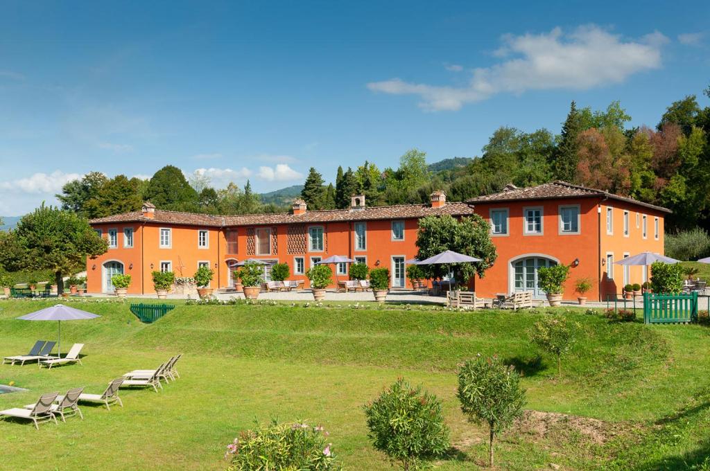 un gran edificio con sillas y un campo de césped en L'Arancera, en Lucca