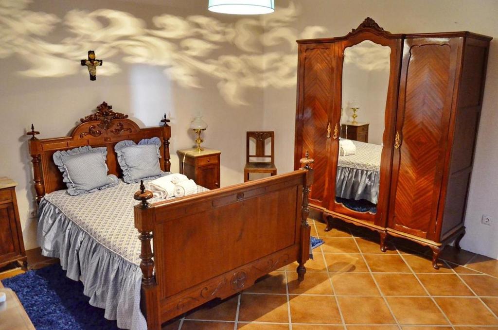 een slaapkamer met een houten bed en een spiegel bij Casa do Avô Zezinho in Monsaraz