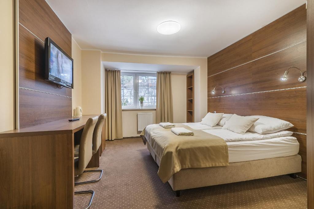 クリニツァ・モルスカにあるPokoje gościnne Nordのベッド、デスク、テレビが備わるホテルルームです。