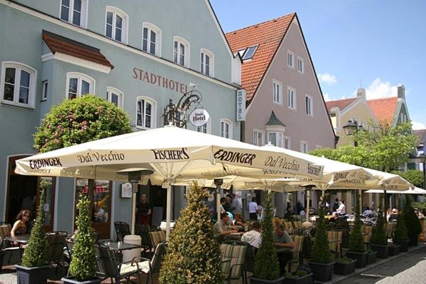 eine Gruppe von Personen, die vor einem Gebäude an Tischen sitzen in der Unterkunft Stadthotel Erding in Erding