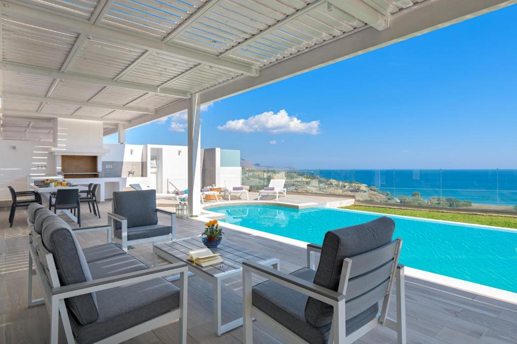 een villa met een zwembad en een tafel en stoelen bij Villa Nissos in Lindos