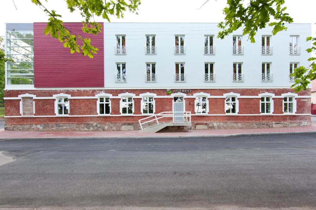 a large red and white building with a staircase at Just Rest Automatic Hostel in Viljandi