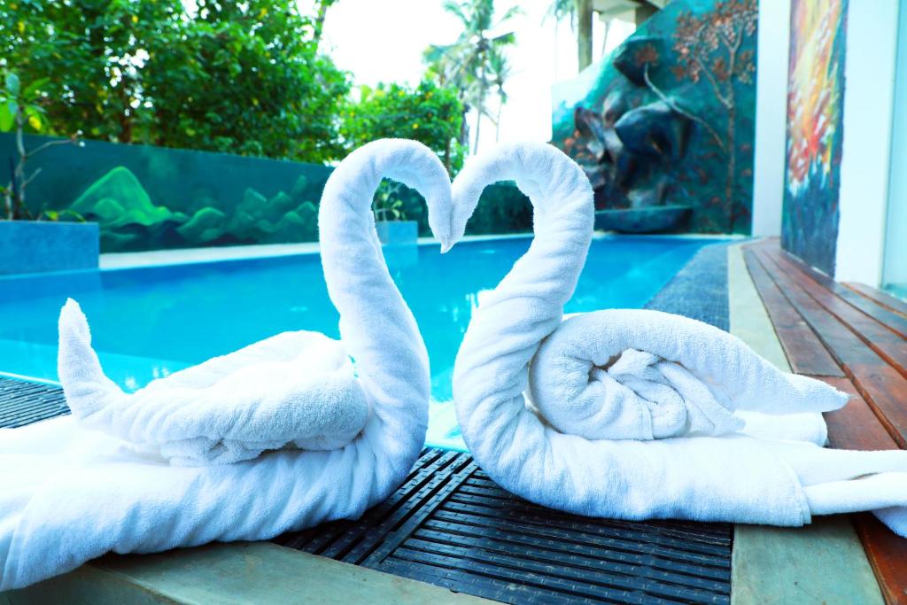 deux cygnes blancs assis sur une table près d'une piscine dans l'établissement Hotel Sanmark, à Ahangama