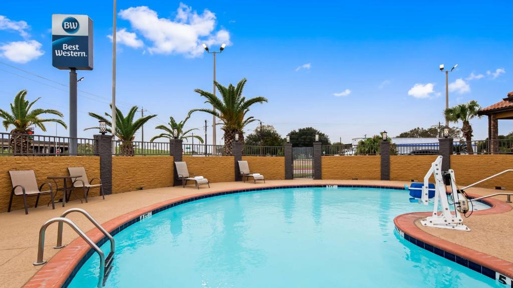 a swimming pool at a hotel with chairs and trees at Best Western Executive Inn El Campo in El Campo