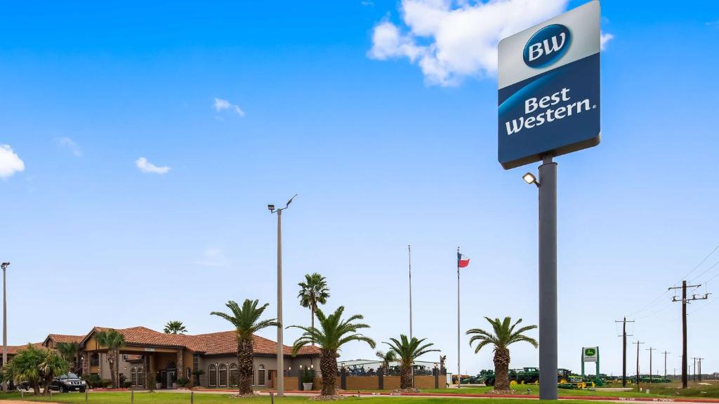 um sinal para um posto de gasolina com palmeiras em Best Western Executive Inn El Campo em El Campo