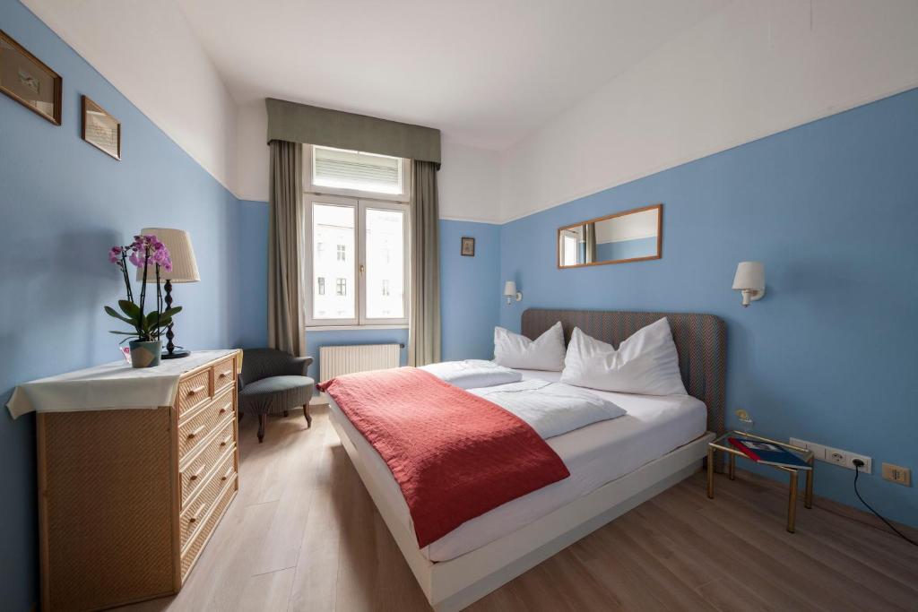 ウィーンにあるモンディアル アパルトマン ホテルの青い壁のベッドルーム1室、ベッド1台(赤い毛布付)