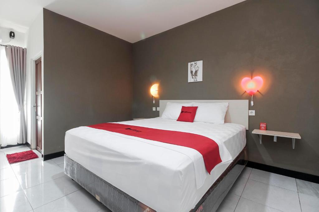 1 dormitorio con 1 cama grande con manta roja en RedDoorz At Jalan Bukit Keminting en Palangkaraya