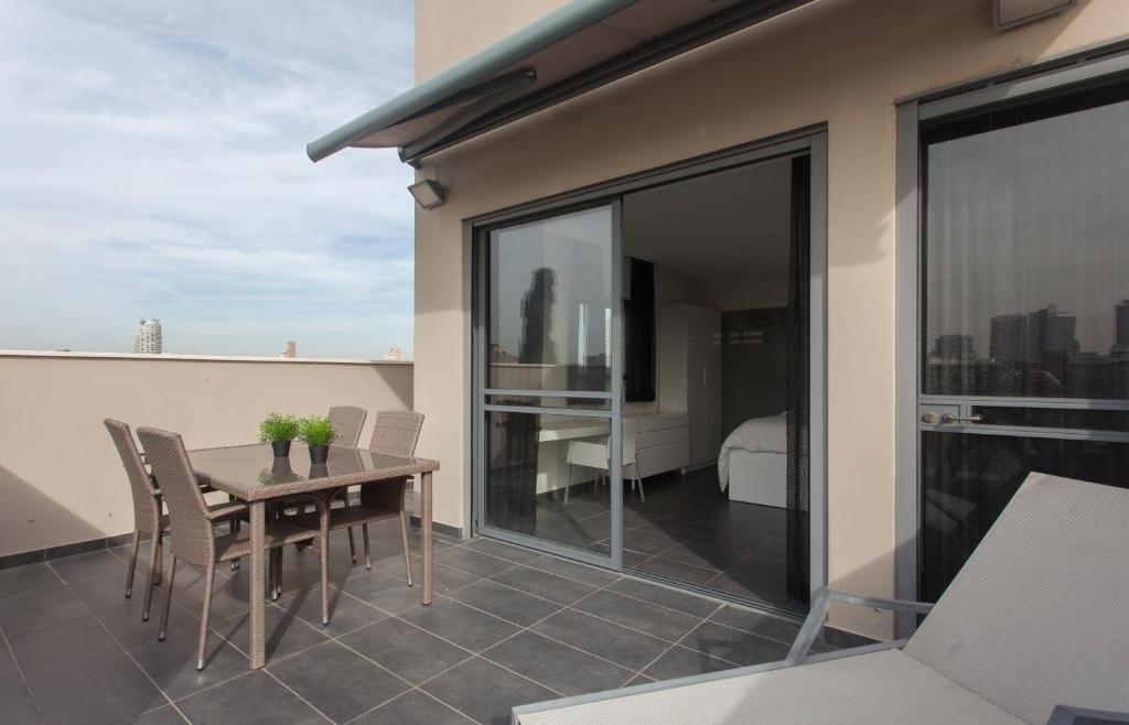 Un patio con una mesa y sillas en un balcón. en Luxury Penthouse 2 bed near Rothchild, en Tel Aviv
