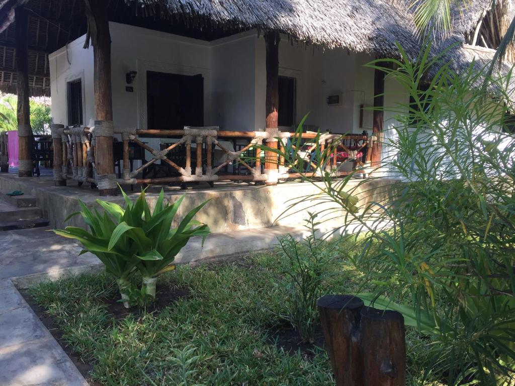 ein Haus mit einer Veranda und einem Grasdach in der Unterkunft Hibiscus in Mambrui in Mambrui