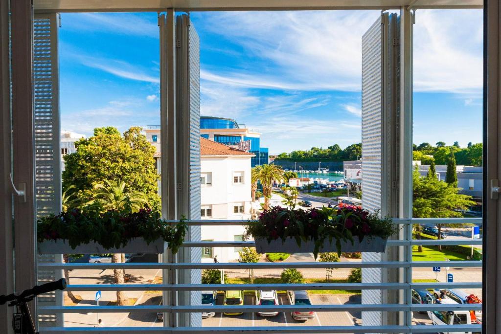 una ventana con vistas a la ciudad y flores en White Towers Residences, en Zadar