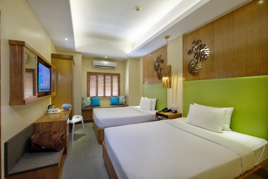 a hotel room with two beds and a television at BE Resort Mactan in Mactan