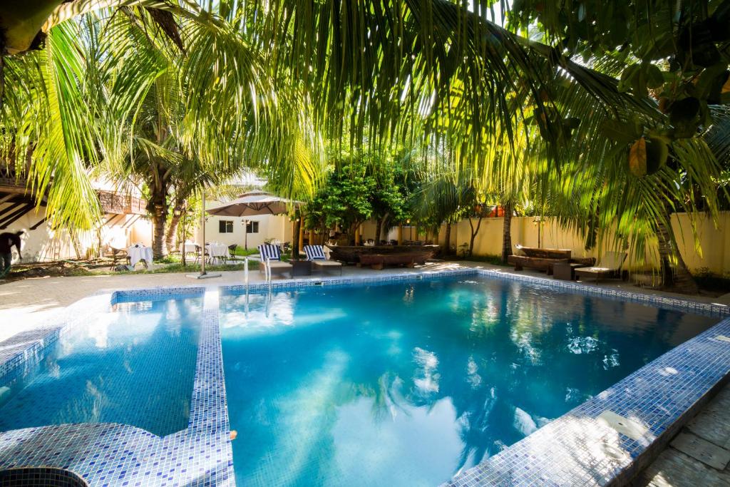 a large swimming pool with a palm tree overhead at Antonio Garden Hotel in Zanzibar City