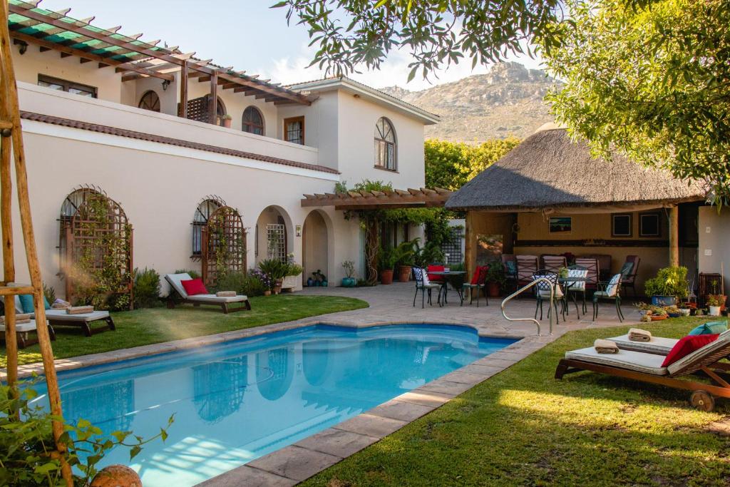 un patio trasero con piscina y una casa en A Tuscan Villa Guest House, en Fish Hoek