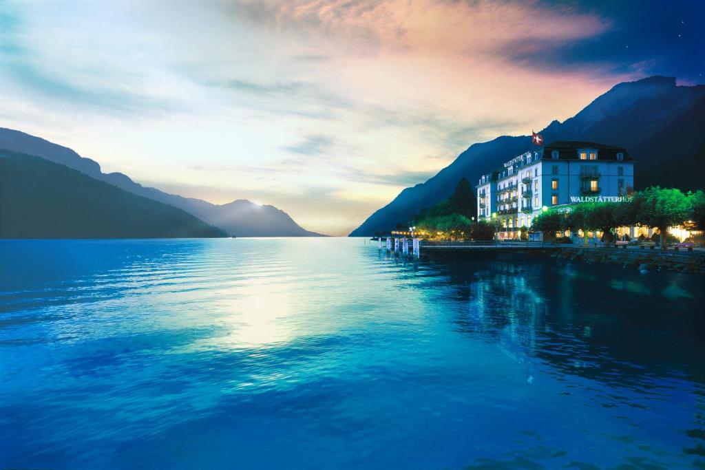 a building on the shore of a body of water at Seehotel Waldstätterhof Swiss Quality in Brunnen