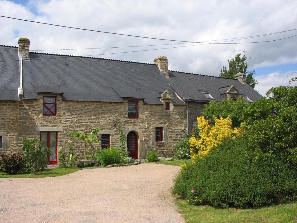 una casa de piedra con techo gris y puertas rojas en Gites du ROHERAN, en Malansac
