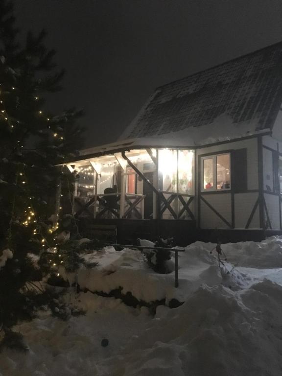 una casa cubierta de nieve por la noche con luces de Navidad en House Panoramy, en Kruglino