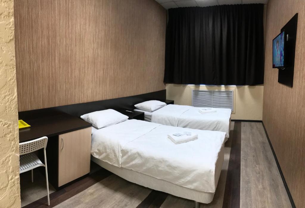 SeveromorskにあるMurmansk Discovery - Hotel Kompasのベッド2台とデスクが備わるホテルルームです。