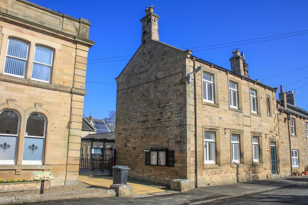 um antigo edifício de tijolos ao lado de outro edifício de tijolos em Newbrough Bunkhouse em Hexham