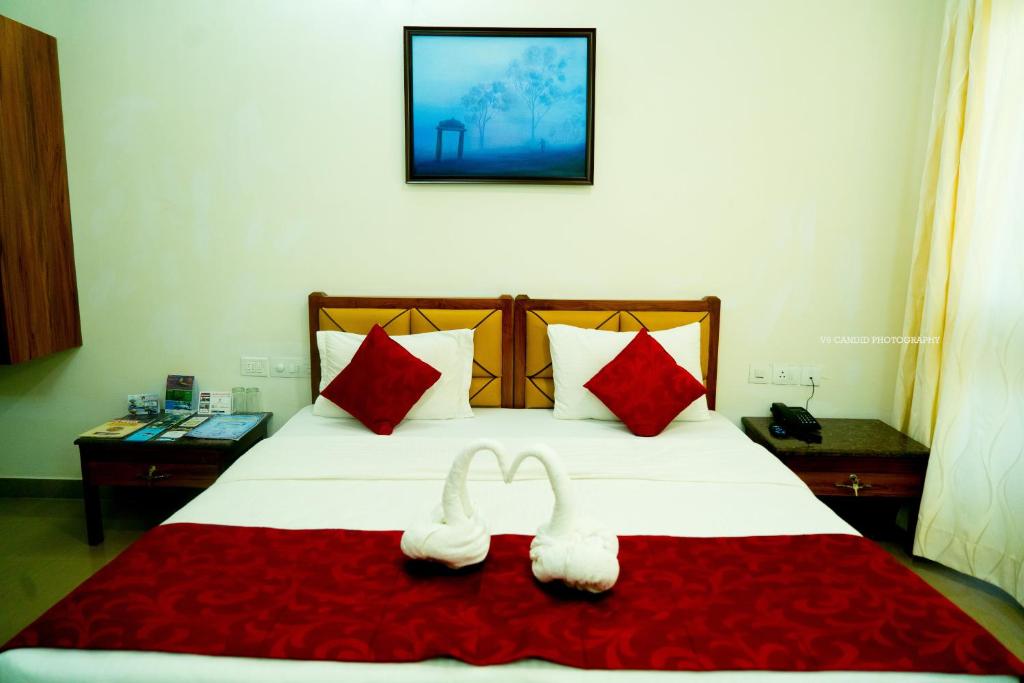 two white towels on a bed with red pillows at KSTDC Hotel Mayura Pine Top Nandi Hills in Nandi