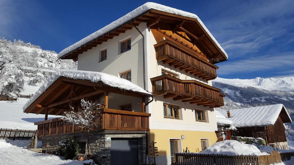 KaunsにあるApart Ferienglückの雪中の木製バルコニー付きの建物