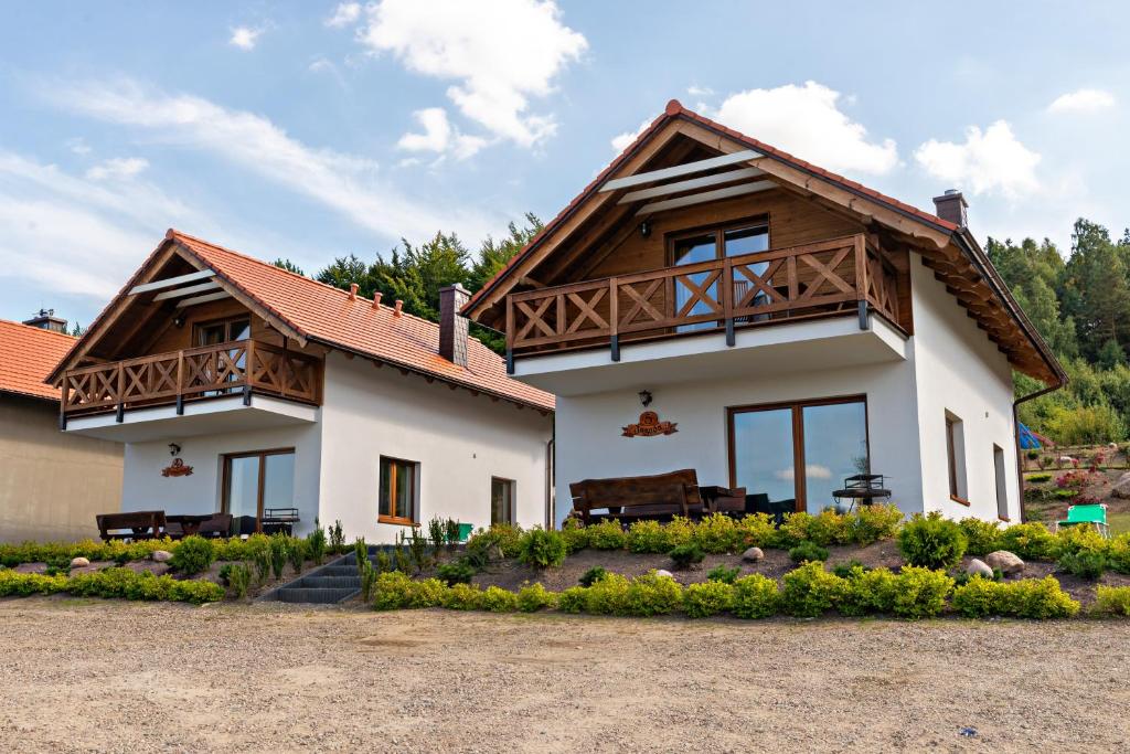 uma casa com uma varanda em cima em Malinowe Wzgórze domki 90 m2 z sauną i balią- płatna em Krzeszna