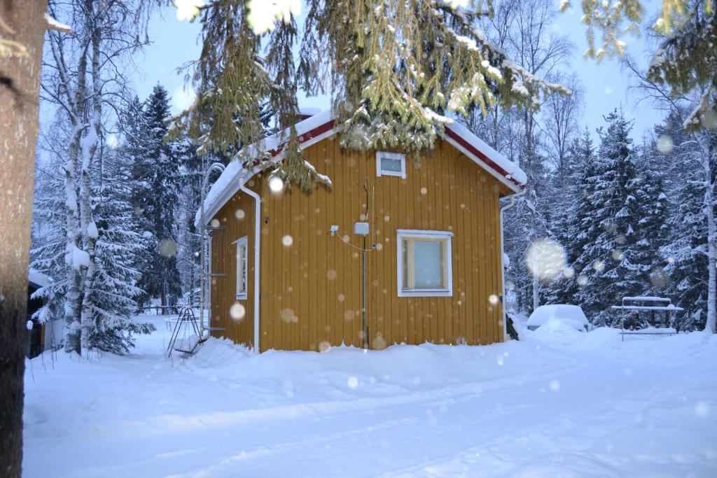 een houten hut in de sneeuw in een bos bij Villa Seven in Rovaniemi