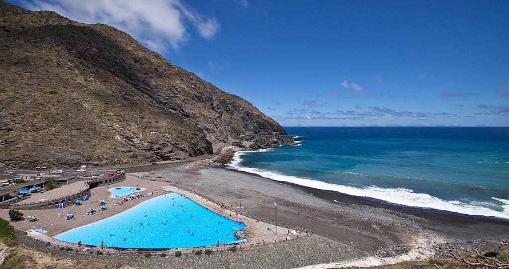 a beach with two swimming pools and the ocean at Hotel Rural Triana in Vallehermoso