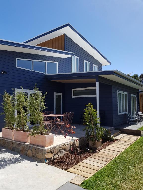 une maison bleue avec une table en face dans l'établissement Zeally Bay Stay Deep Ocean, à Torquay