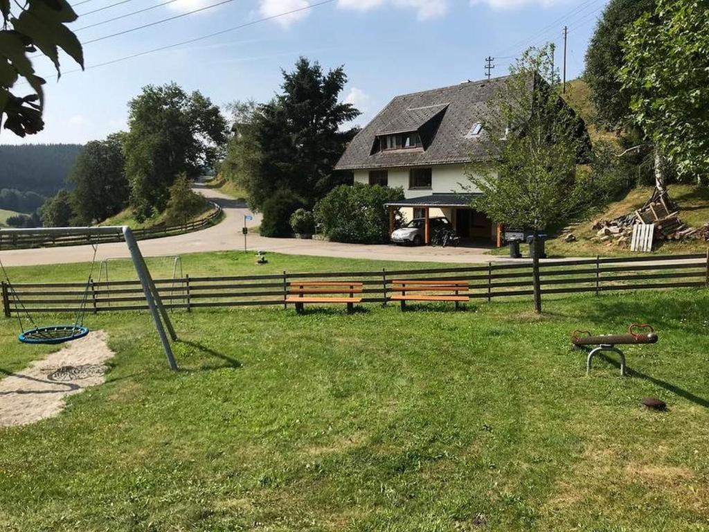 ティティゼー・ノイシュタットにあるFerienhaus Robinの芝生の上に二つのベンチを持つ丘の上の家