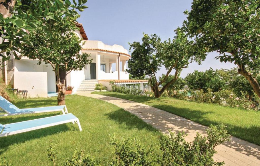 a white house with a garden and a bench at Meravigliosa casa con vista Tropea in Santa Domenica
