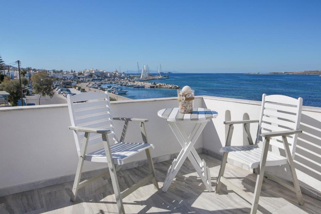 2 stoelen en een tafel op een balkon met uitzicht op het water bij Alexandra's Rooms in Parikia