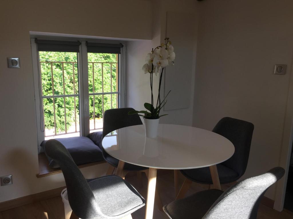 una mesa blanca y sillas con un jarrón de flores. en Gîte des Charmilles /La Maison des Gardes en Cluny