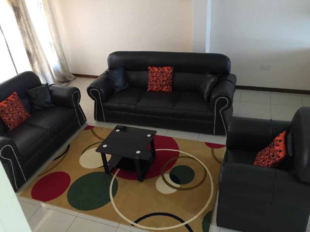 a living room with a couch and a table on a rug at The Gibeon Ville Self-Catering in Gaborone