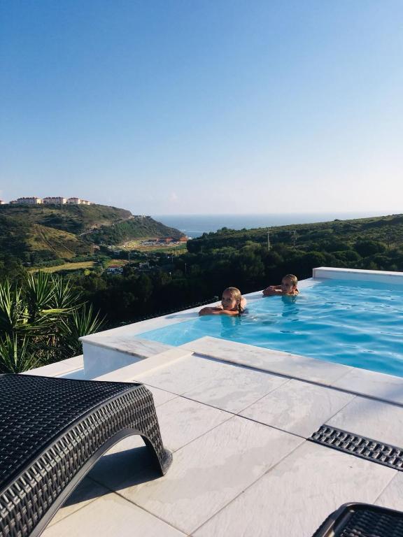 two people in a swimming pool with the ocean in the background at Casa Tazmin in Santo Isidoro