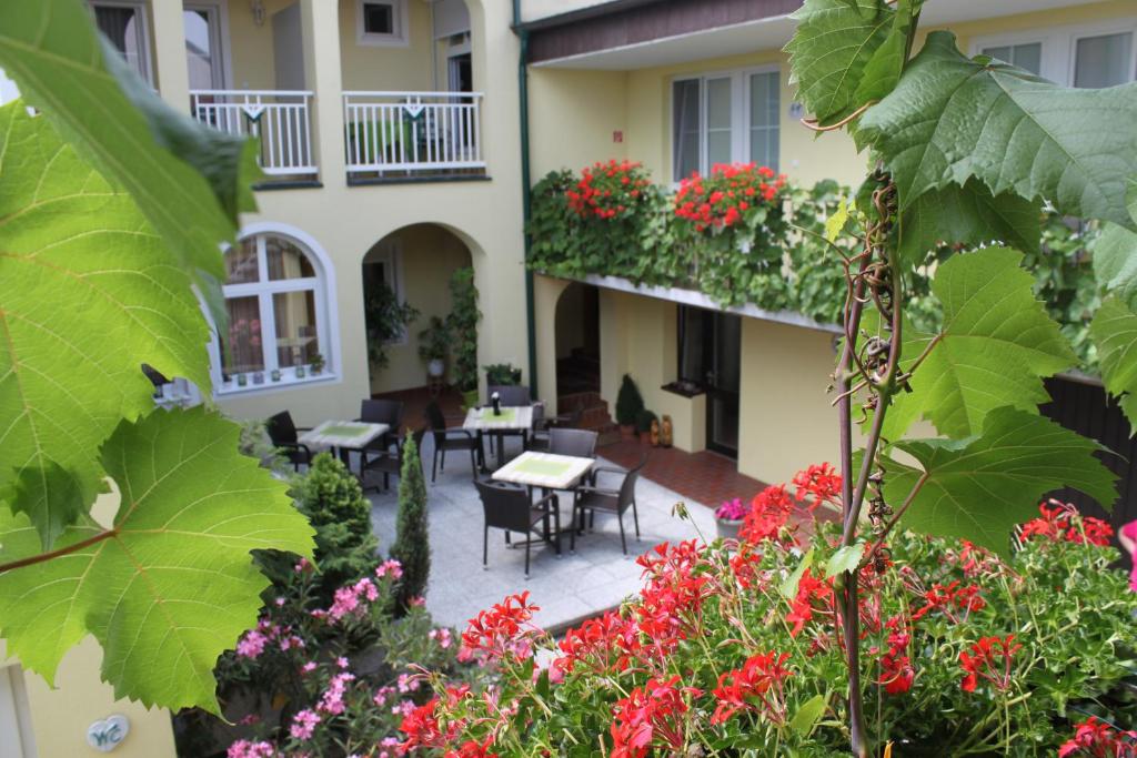 a courtyard of a building with flowers and tables at Pension Peterhof in Mörbisch am See