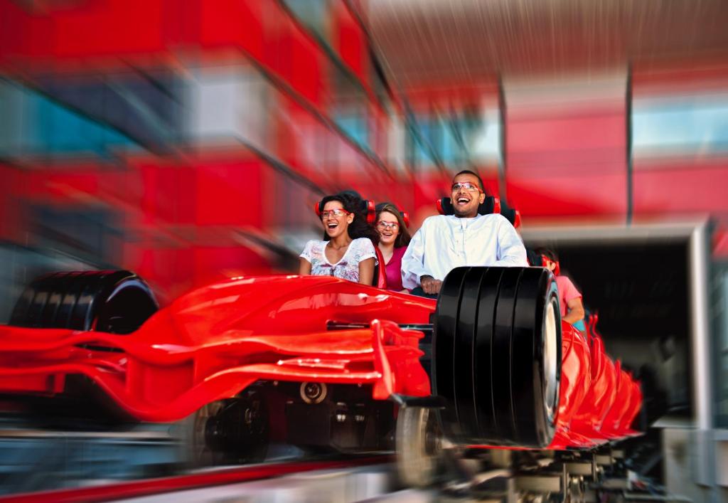 a group of people standing next to a red car at Yas Island Rotana Abu Dhabi in Abu Dhabi
