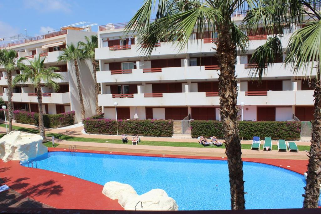una piscina frente a un edificio con palmeras en Gwen El Rincon, en Playa Flamenca