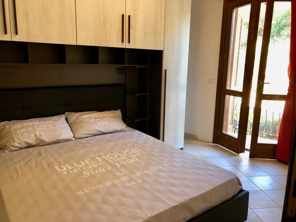 łóżko w sypialni z dużym oknem w obiekcie Calypso Home Sea View w mieście Badesi