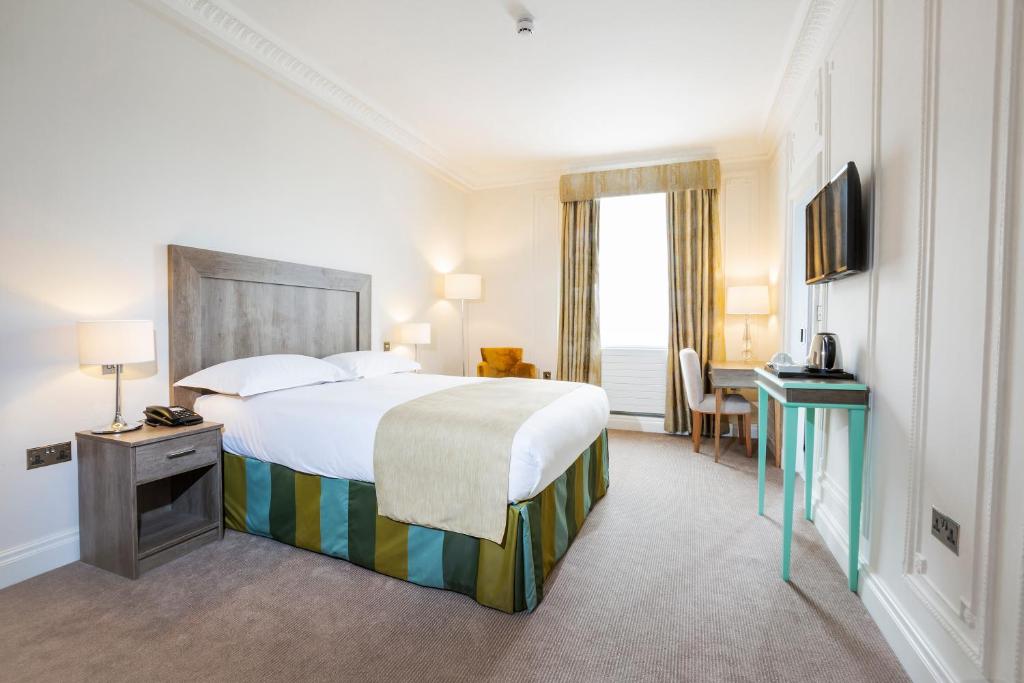 una camera d'albergo con letto, scrivania e TV di Astor Court Hotel a Londra