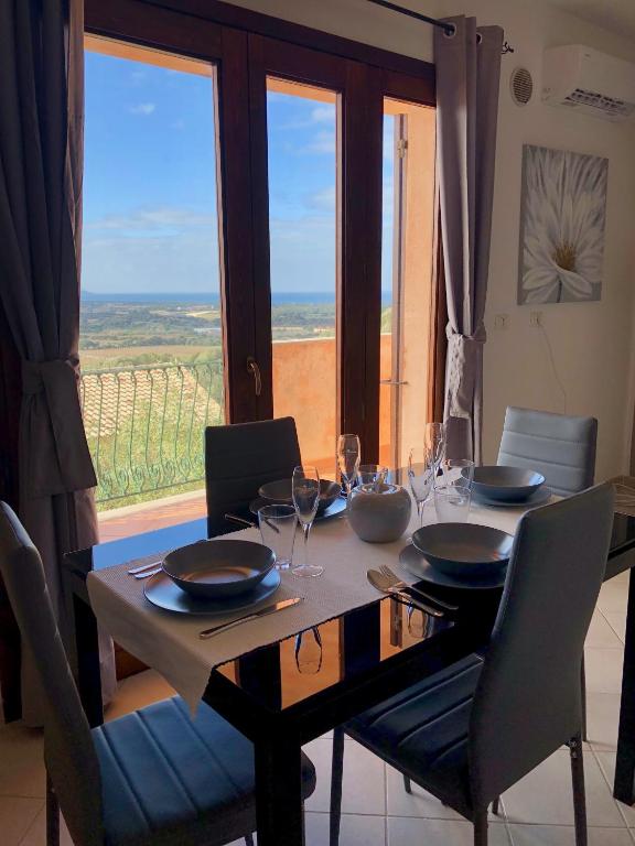 stół jadalny z krzesłami i duże okno w obiekcie Calypso Home Sea View w mieście Badesi