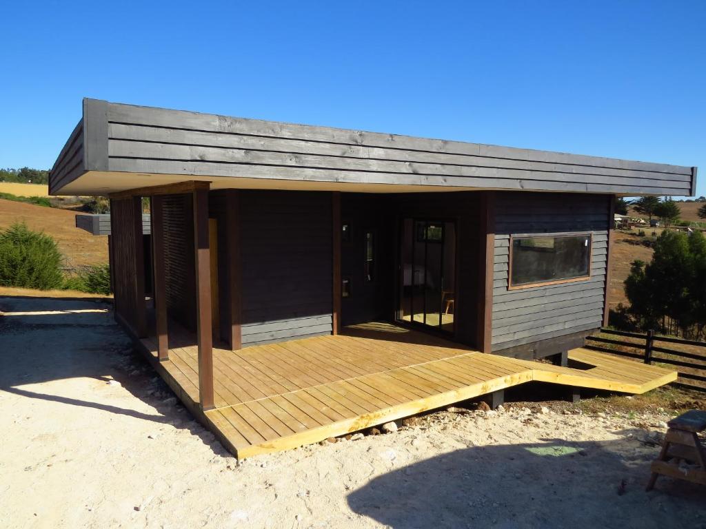 een kleine hut met een houten terras in een veld bij Punta Sal Pichilemu in Pichilemu