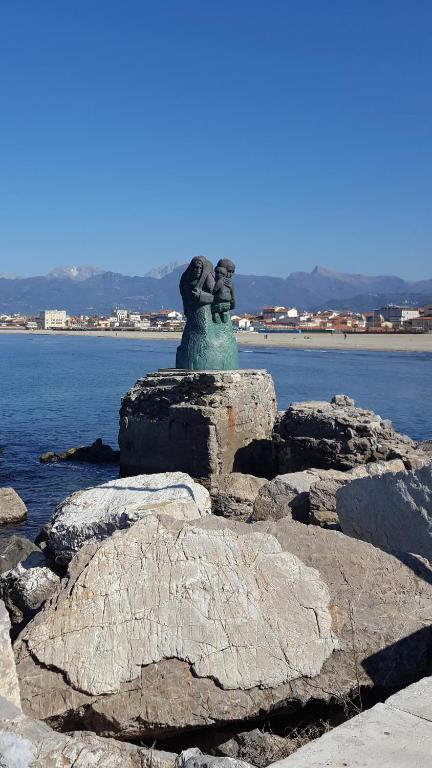 una estatua sentada sobre rocas cerca del agua en Hotel Sauro, en Viareggio