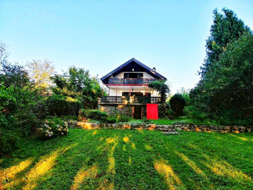 a house with a red door in a yard at Kuća za odmor &quot;Livadica&quot; in Netretić