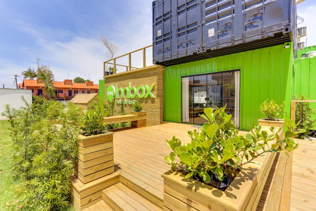 Innbox - Canasvieiras في فلوريانوبوليس: مبنى أخضر وبه نباتات على سطح خشبي