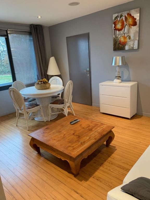 ein Wohnzimmer mit einem Tisch, einem Tisch und Stühlen in der Unterkunft Lumineux T2B a Mont de Marsan in Mont-de-Marsan