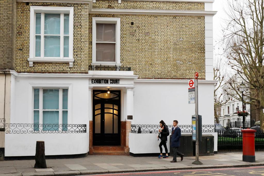 due persone che camminano davanti a un edificio di Kensington Stay a Londra