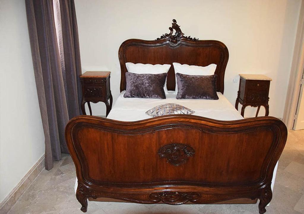 a wooden bed in a bedroom with two night stands at Dar ALOUINI in Kairouan