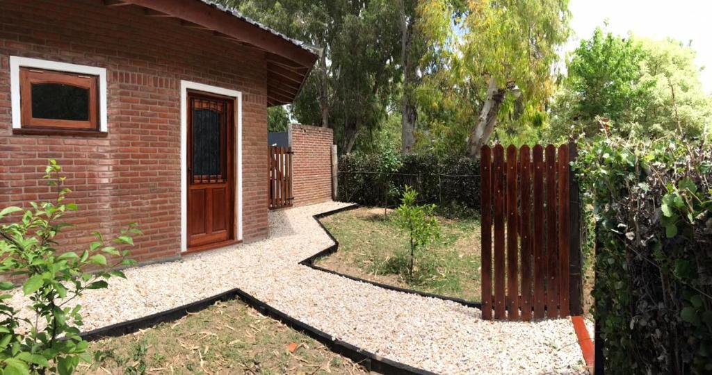 un jardín con un edificio de ladrillo y una puerta de madera en Santa Teresita Sobre El Monte en Santa Teresita