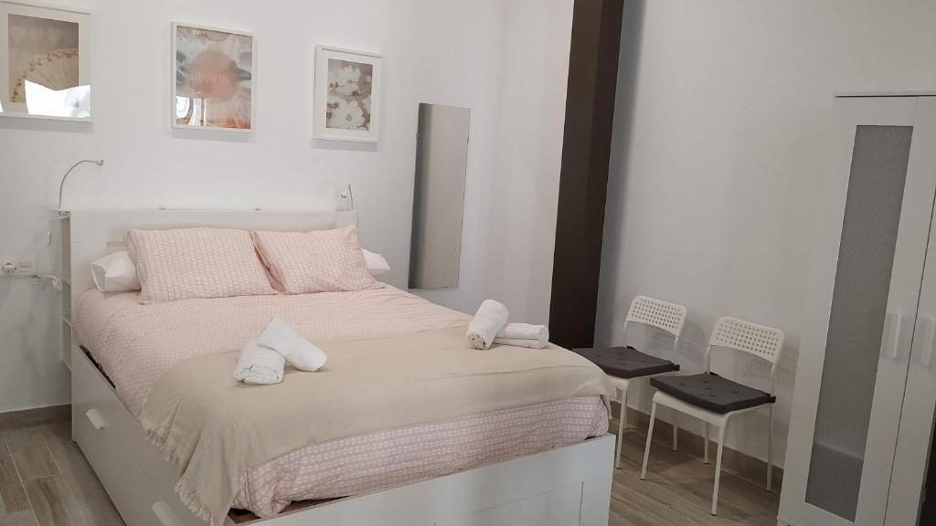 セビリアにあるSuites Jeronimo de Cordobaの白いベッドルーム(ピンクの枕が付いた大型ベッド付)